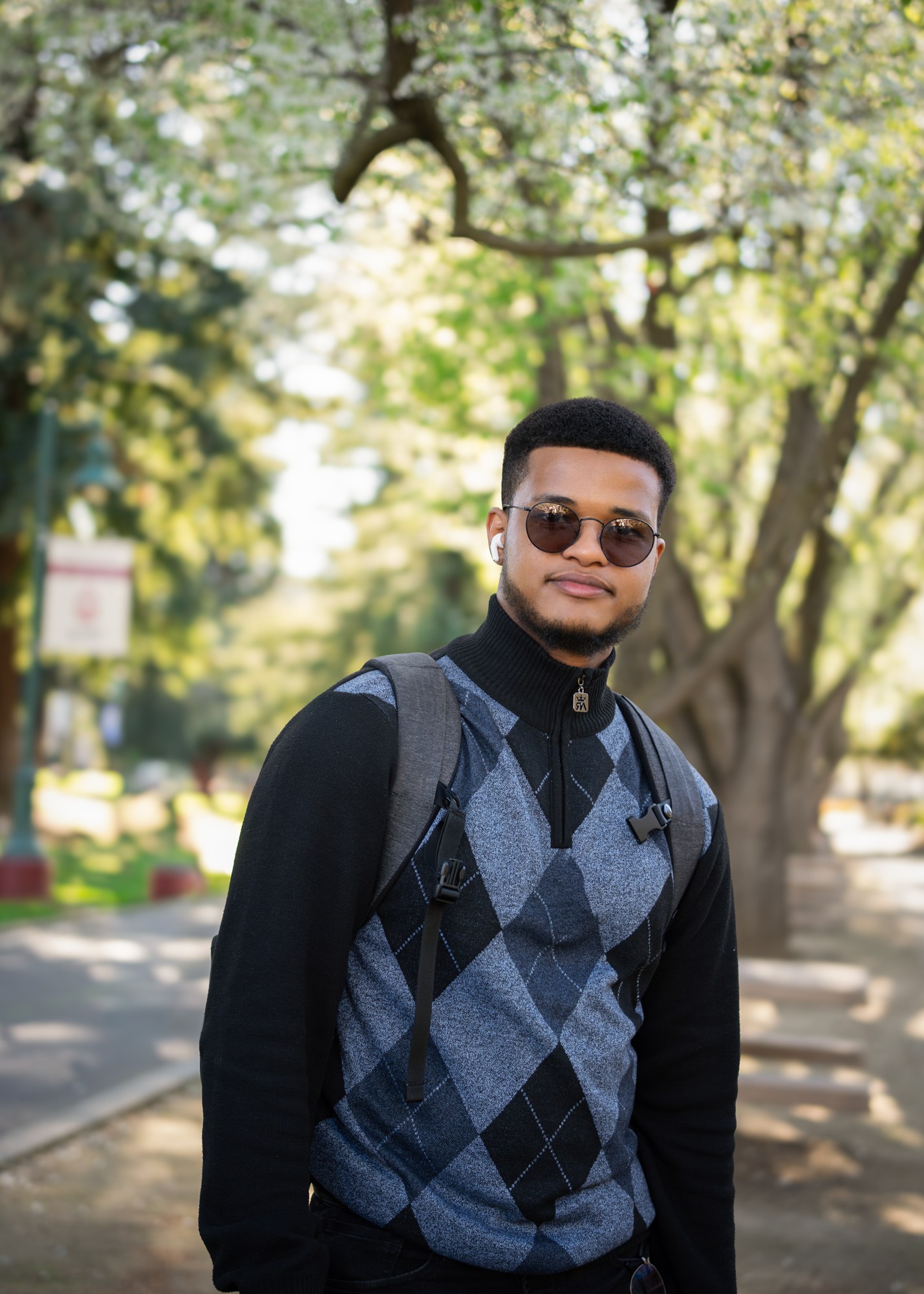 Mo outdoors wearing sunglasses and a patterned sweater