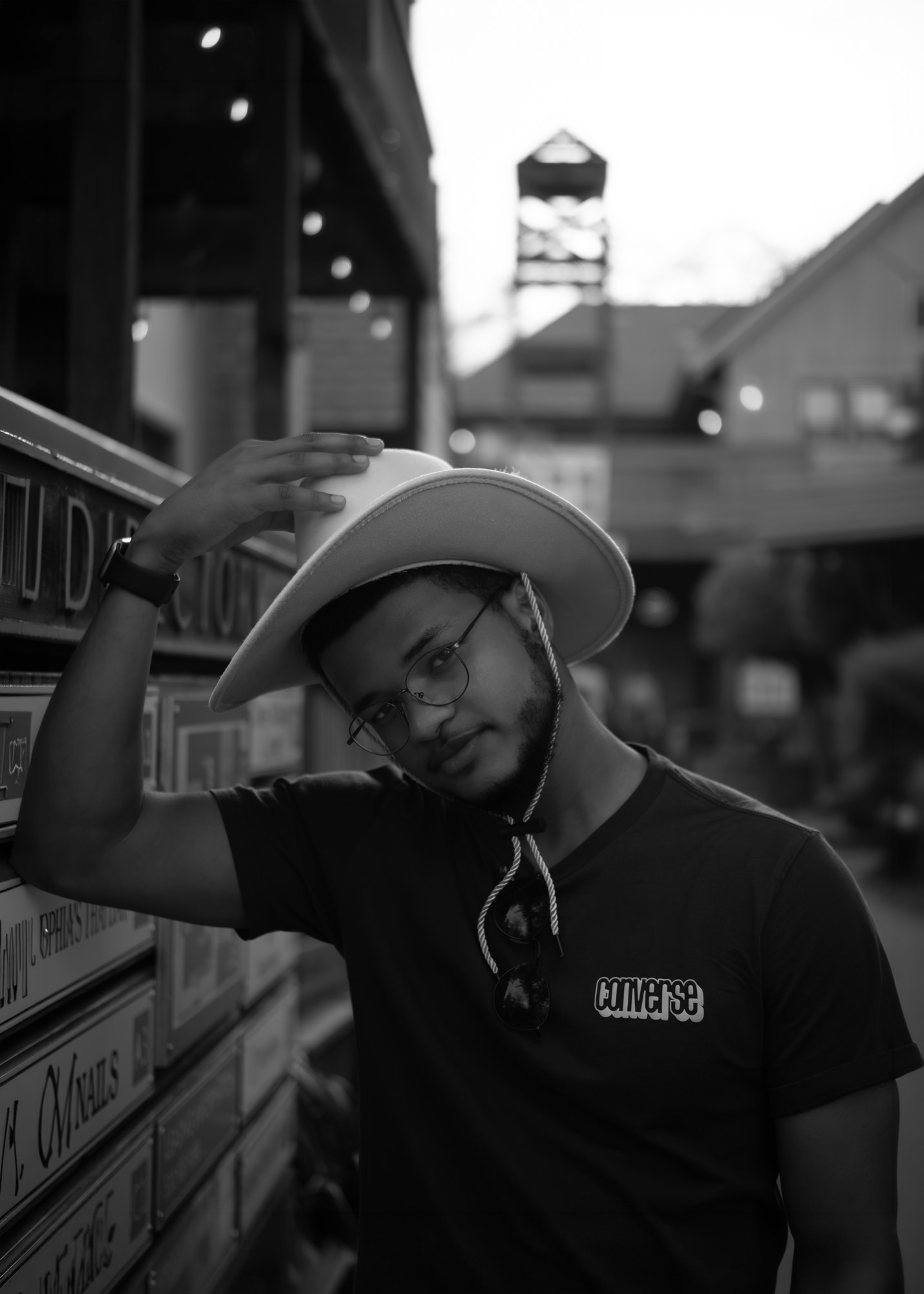 Black-and-white portrait of a person wearing glasses and a wide-brim hat